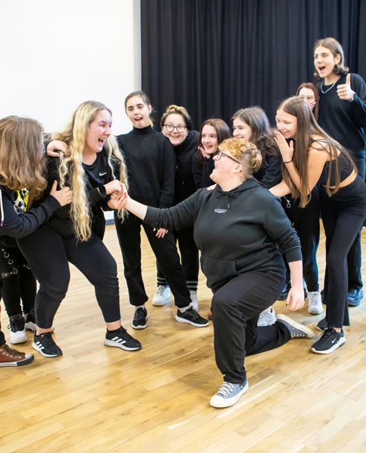 A lively group of students acting out a playful and dramatic scene together, enjoying a theatre exercise filled with laughter A lively group of students acting out a playful and dramatic scene together, enjoying a theatre exercise filled with laughter